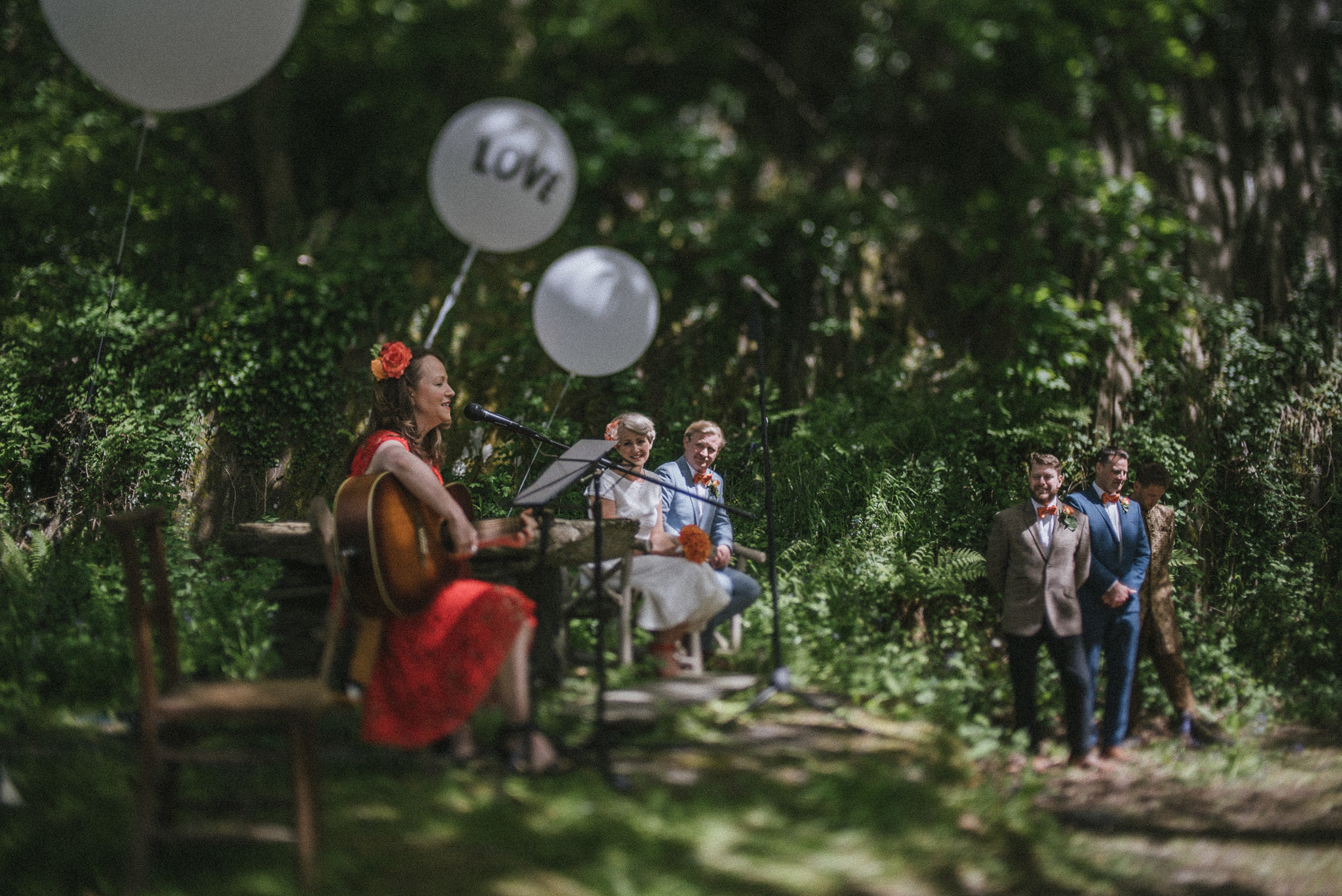 Brides sister plays guitar and sings at open air Fforest Farm wedding ceremony