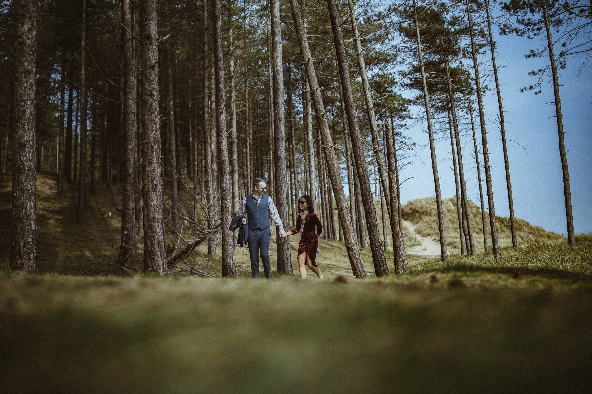 A couple walk amongst Corsican Pine trees at Newborough, Anglesey.