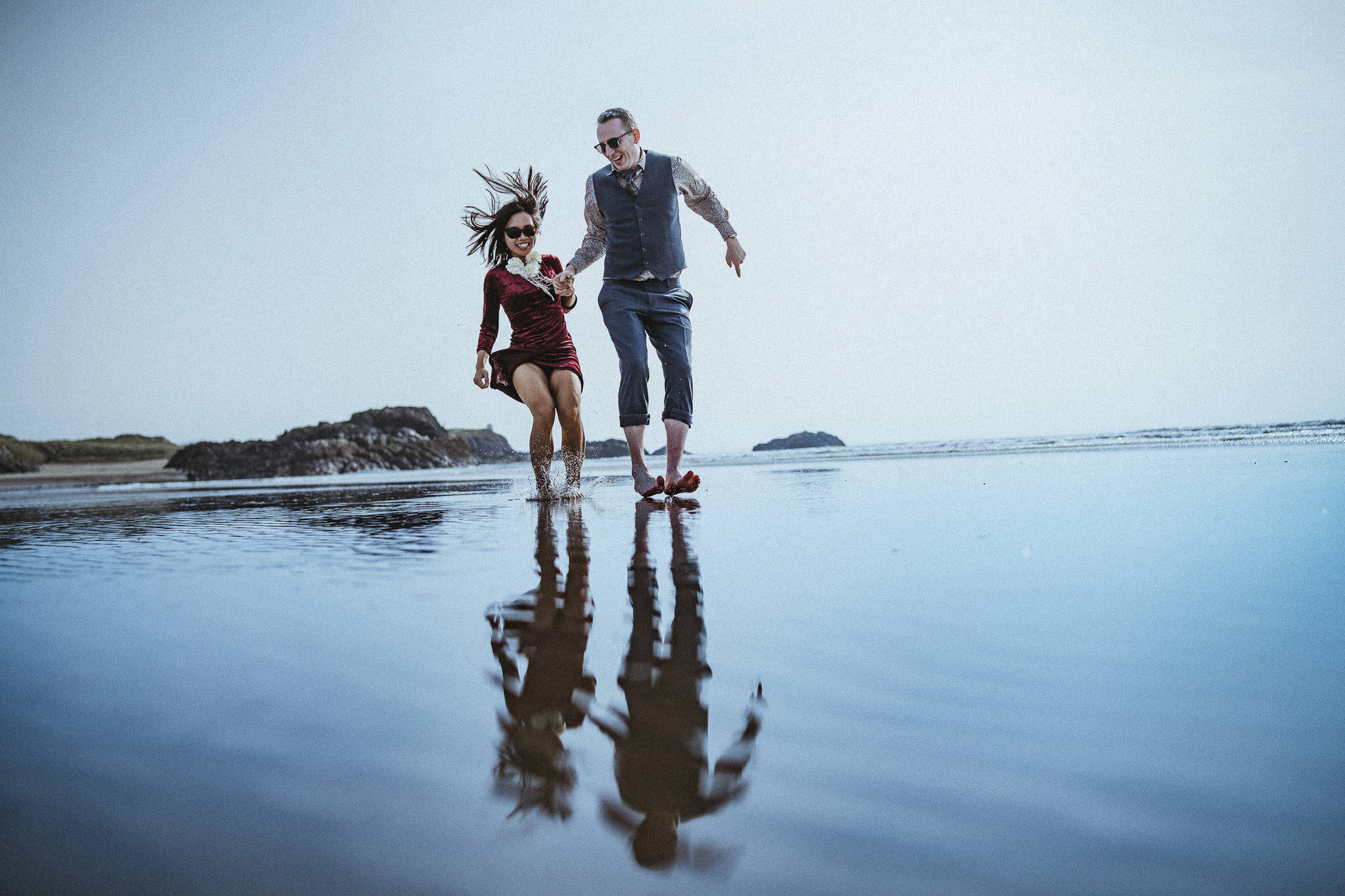 Engagement shoot couple run along beach on Anglesey